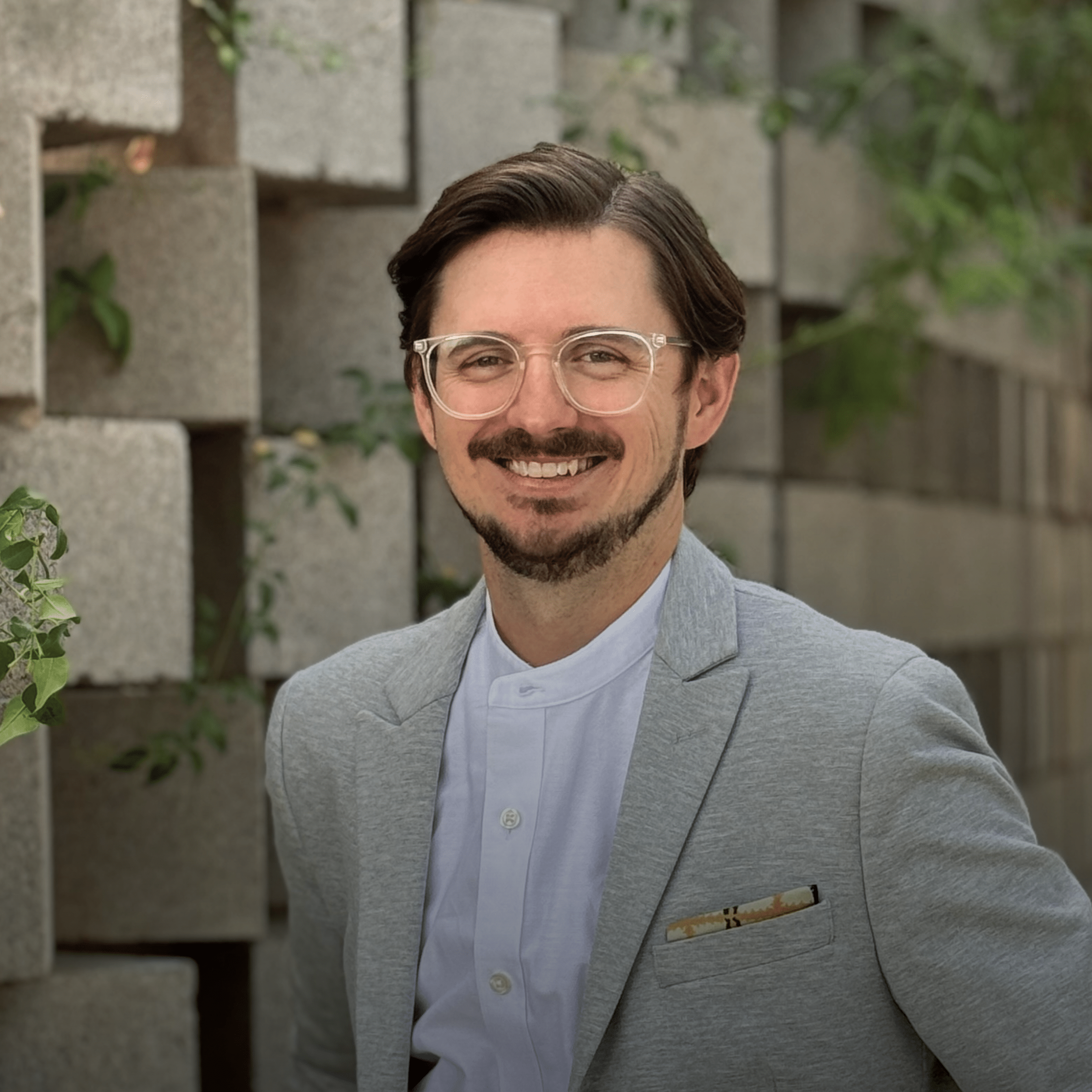 Shawn Swisher, AIA, LEED AP BD+C, Senior Associate at Jones Studio, photographed at the Tempe, Arizona office with textured concrete block architecture in the background.