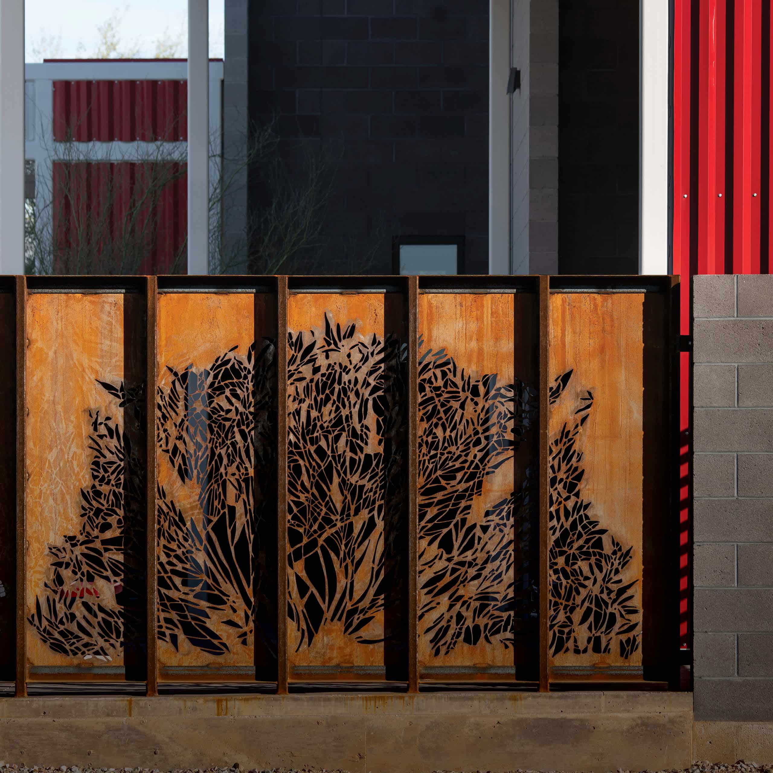 Weathered steel public art panels shape half of a Maltese Cross with pattern cut out designed by Maria Salenger, AIA of Jones Studio.